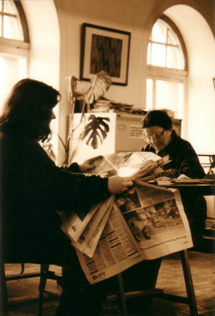 Readers in the 109 Trongate space; one is holding a newspaper, which hides what the other is reading