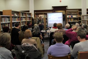 Ajay Close talking about her work to a library full of women.