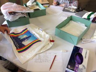 A tshirt from the Lesbian Archive on a table with archive boxes and pieces of paper