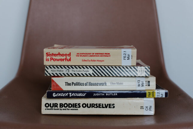 Image of a pile of books including 'Our Bodies Ourselves and 'The Politics of Housework'