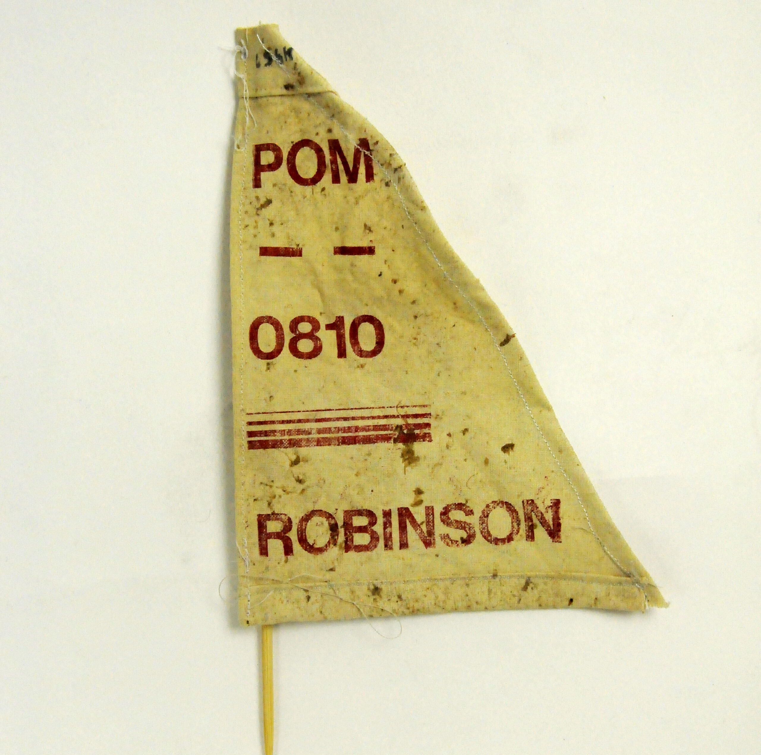 Artwork by Clementine Thomas, looks to be a pennant flag in yellow rough materials with the work 'POM' '0810' and then 'ROBINSON' all in red printed on top.
