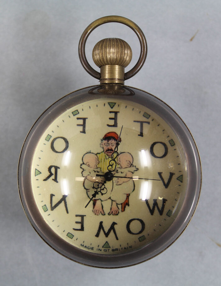 A spherical clock with a cartoon of a man holding two babies, and 'Vote For Women' written backwards around the clockface