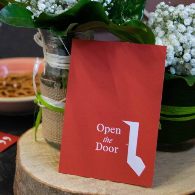 A red postcard with the text 'Open the Door' in white near the bottom.