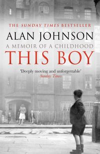 A black and white backrground picture of a street with a woman walking into a house and a young boy looking at her in the foreground. The title of the book "This Boy" is witten in big, red bold letters across the picture.