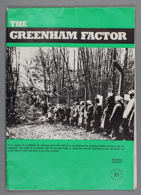 A green booklet with a black and white image across its centre. The image shows people standing against a fence that is topped with barbed wire.