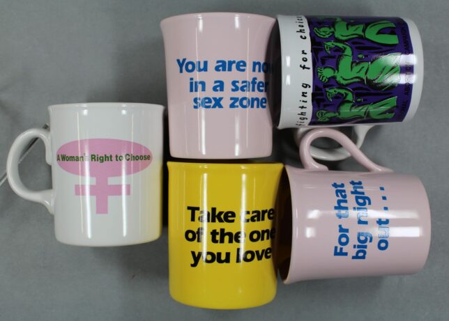 Five mugs arranged in a cluster. One reads, "You are in a safer sex zone" and another is a pro-choice mug from the National Abortion Campaign.