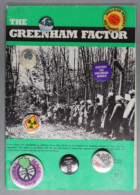 The Greenham Factor booklet with anti-nuclear and peace campaign badges sitting on top of it.