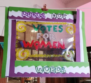 Handmade suncatcher in suffrage colours and with 'votes for women' written on the clear plastic 