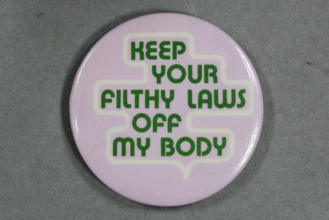 A badge that states: "Keep Your Filthy Laws Off My Body", green lettering on a lilac background.