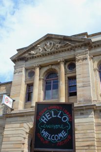 A photo of the front of GWL, with a blackboard sign saying 'Hello, Everyone Welcome' in front.