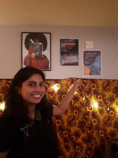 A woman standing in a shop in front of some posters.