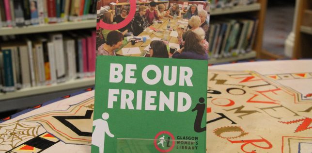 A display of GWL Friends leaflets with the title 'Be Our Friend' stands on a colourful table with bookshelves behind.