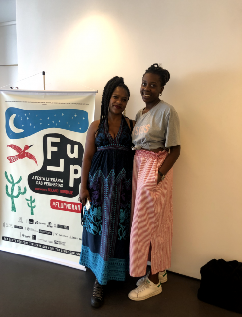 Two women standing side by side in front of a FLUP banner.