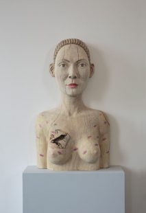 Wood carving of a woman's face and torso.