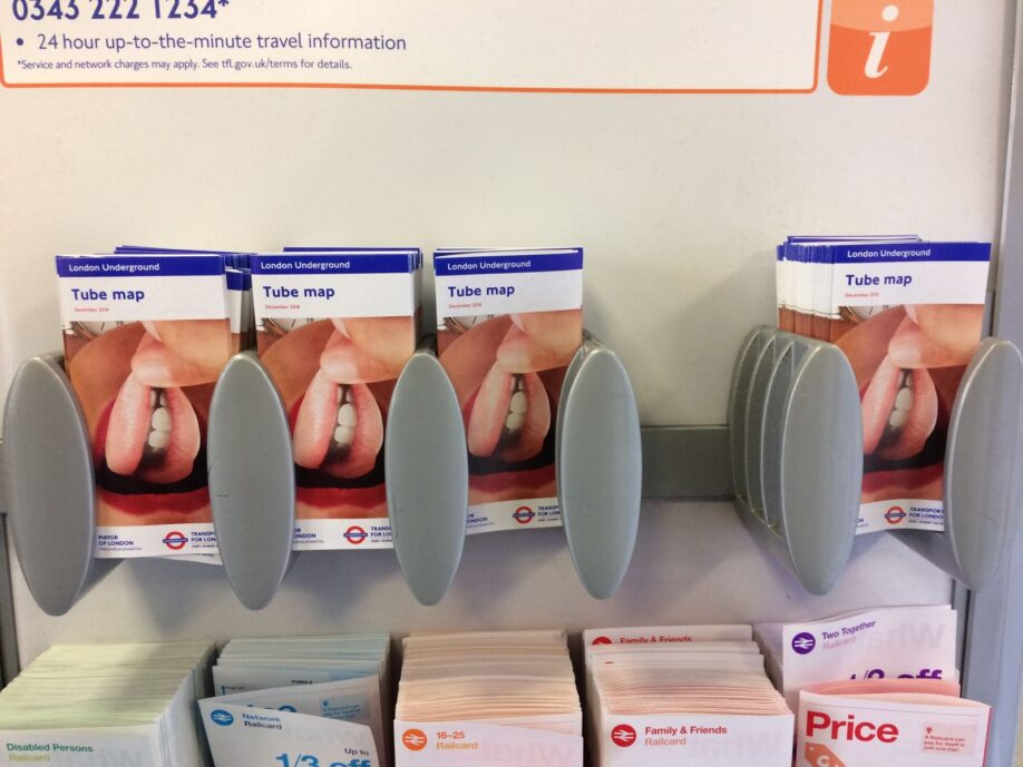 Detail of London tube maps designed by Linder. The map covers have collages of women's mouths, an iconic element of Linder's work; the text of the maps is the standard Transport for London format, and they're in an aging grey plastic display
