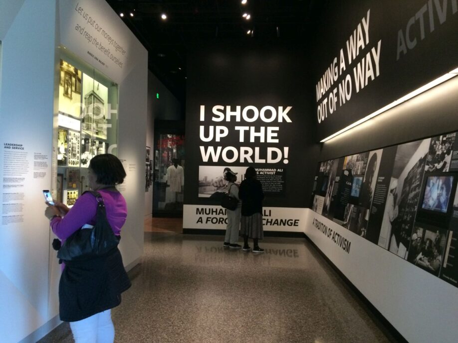 Interior of National Museum of African American History and Culture, Washington D.C., 24th March, 2019. There are photos of black activists on the walls, and a large caption in bold white capitals on a black background that reads 'I shook up the world!'