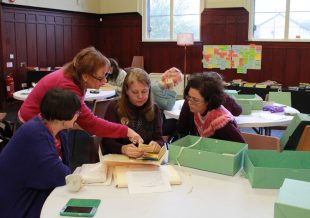 In the GWL main event space, some of the community curators look at small items from the collection. 