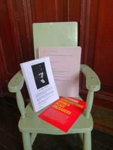 Two books, one with a black and white portrait of Helen Crawfurd on its cover, sit on a small chair.