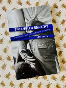 Book cover with a black and white image of a human hand holding on to a young chimp