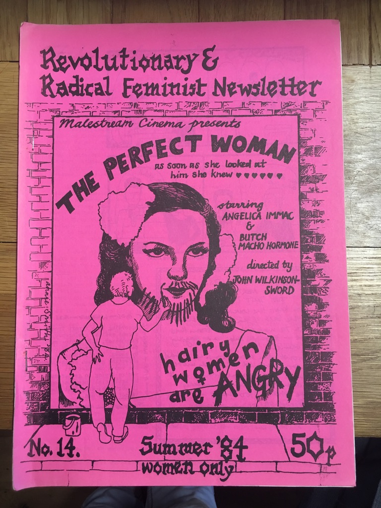 A bright pink cover of the feminist newsletter with black writing and a black drawing of a movie poster with a woman graffitiing a beard onto the movie star on the poster. She has also scribbled, ‘hairy woman are angry’ in the corner of the poster.