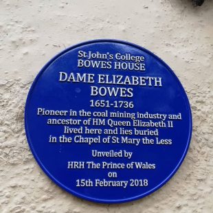 Circular blue plaque with white writing commemorating Dame Elizabeth Bowes, 1651-1736. It says: "Pioneer in the coal mining industry and ancestor of HM Queen Elizabeth II lived here and lies buried in the Chapel of St Mary the Less. Unveiled by HRH The Prince of Wales on 15th February 2018"