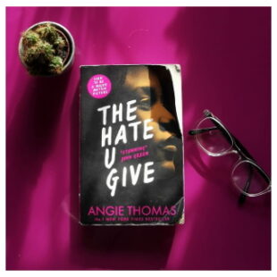 a small potted cactus sits at the top on the image. at the centre is the book "THE HATE U GIVE" beside which to the right is a pair of glasses