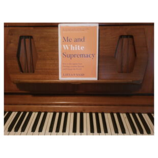 the book "Me and White Supremacy" sits on a piano