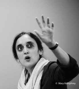 Portrait of Gauri Raje holding her hand up to the camera mid-performance. Gauri Raje. Credit: Mary Humphrey