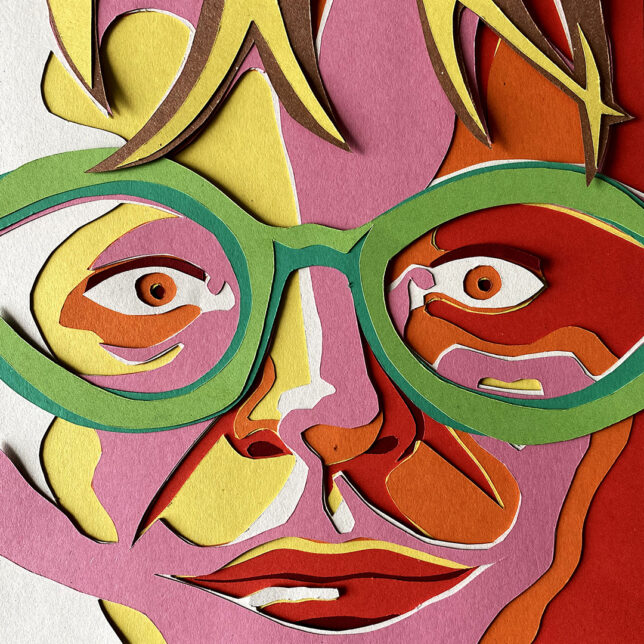 Cropped, paper cut-out portrait of Edith Simon close-up looking straight at viewer with red, orange, pink, yellow and white paper for her face and green for her oversized glasses.