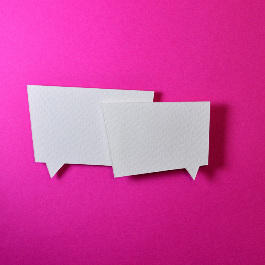 two papercut outs of speech bubbles sit on top of a shocking pink background