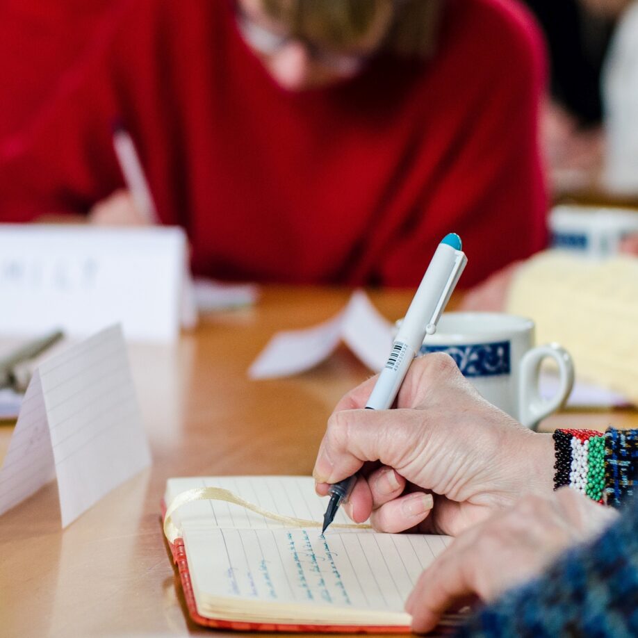 A close up of a hand with pen which is writing in a note pad