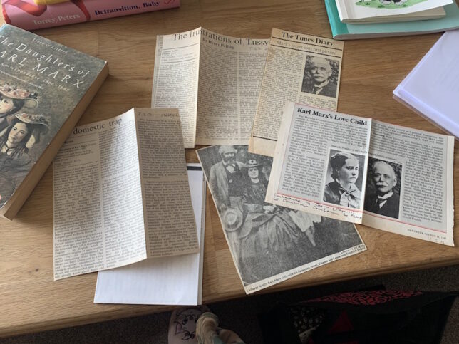 Image shows multiple newspaper clippings of Marxist history laying across a table.