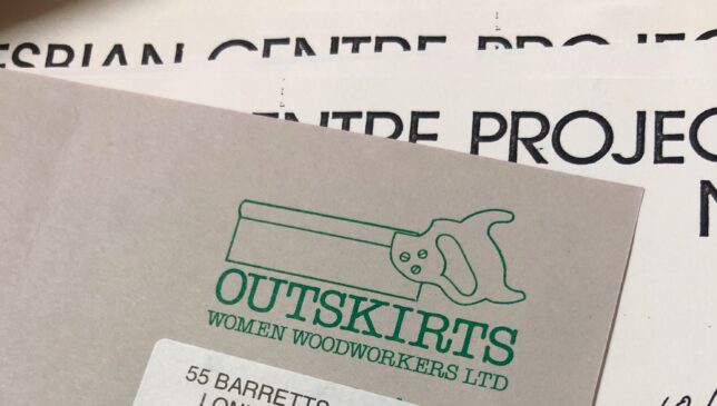 Letterhead for Outskirts Women Woodworkers Ltd, featuring their name in block serif font below a simple outline drawing of a saw, all in forest green ink on light grey paper.