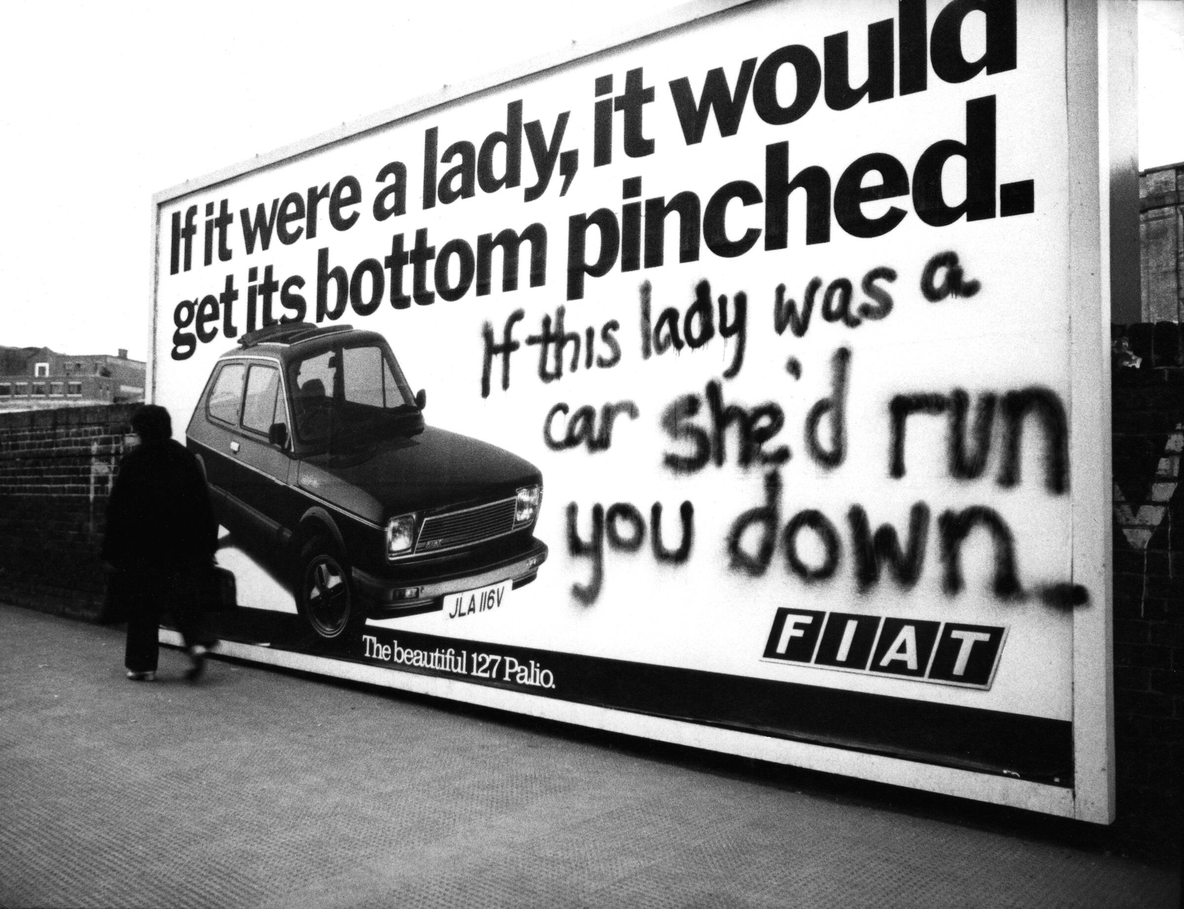 A billboard advert for a Fiat 127 Palio, featuring an image of the car in the bottom left corner and the slogan 'If it were a lady, it would get its bottom pinched.' Beneath this, someone has spray-painted 'If this lady was a car she'd run you down.'