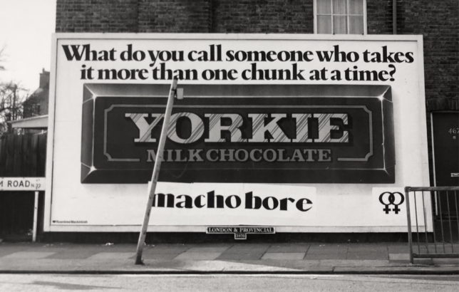 Billboard for Yorkie chocolate, featuring image of the chocolate bar in centre and text above it that reads, 'What do you call someone who takes it one chunk at a time?' Below the bar, someone has wheat-pasted the answer: 'macho bore'.