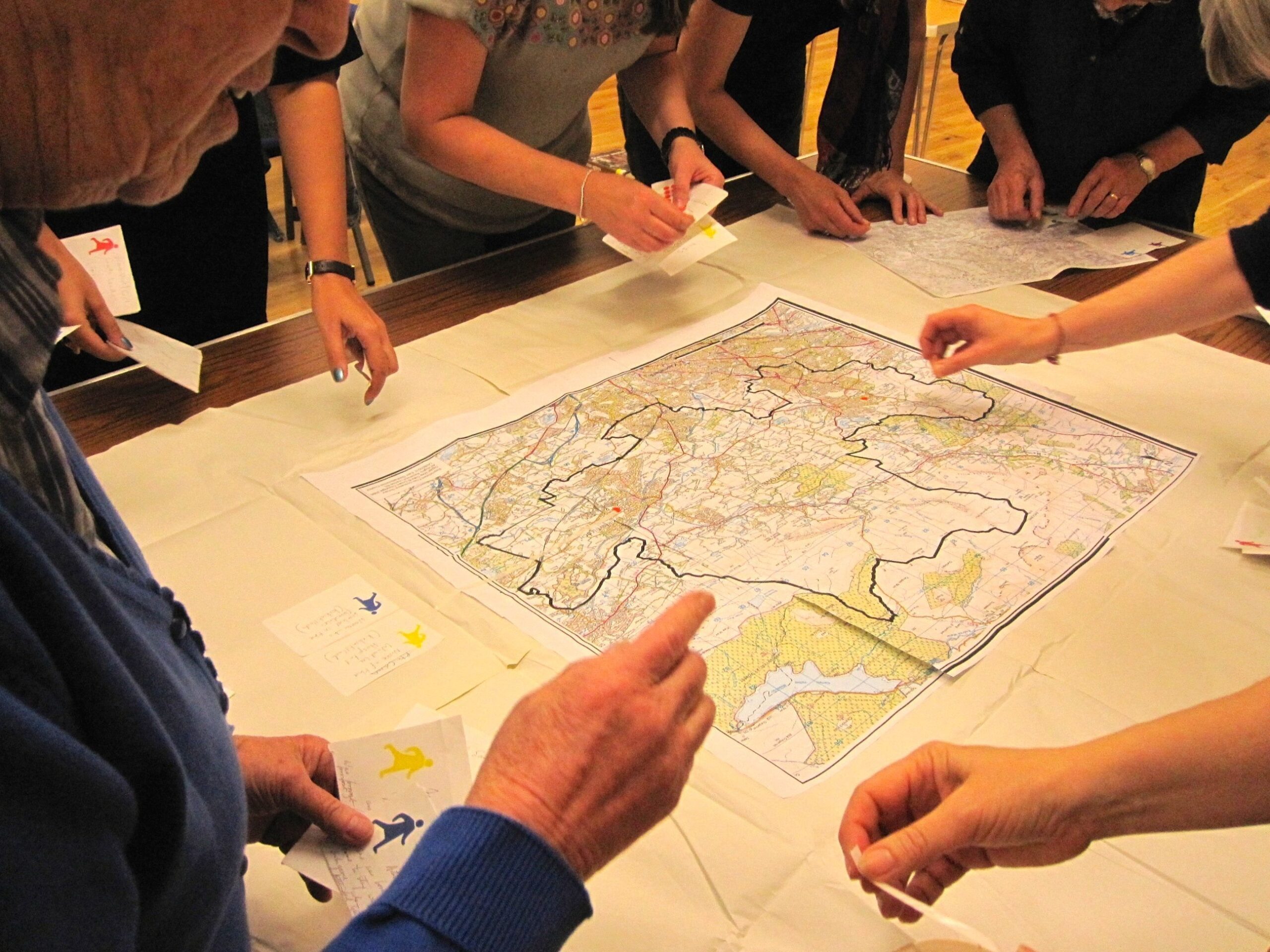 Workshop attendees reach into a tabletop map to place position markers