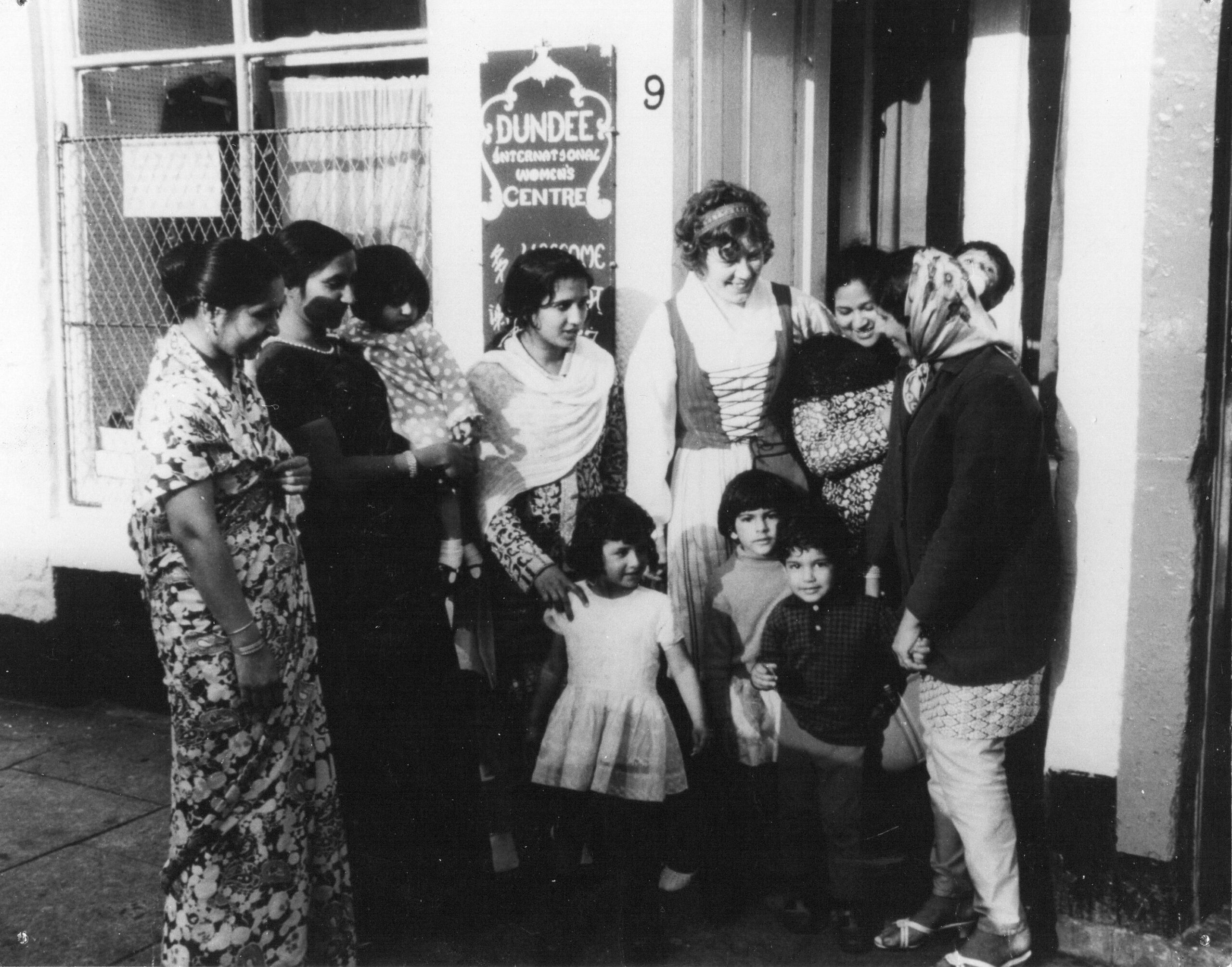 A black and white image of a group of women and children standing in front of the Dundee International Women's Centre