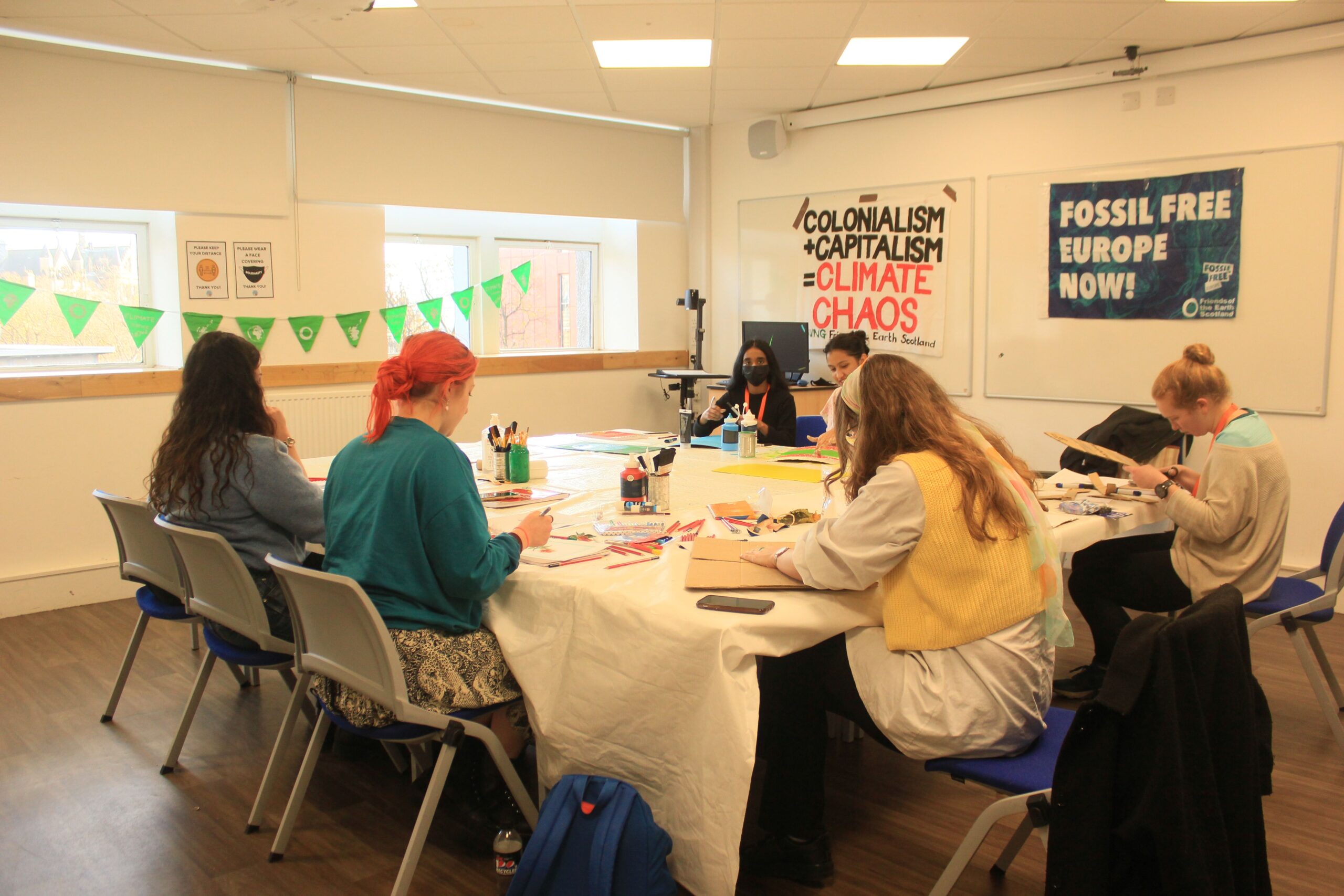 The image is of a group of people round a table creating zines
