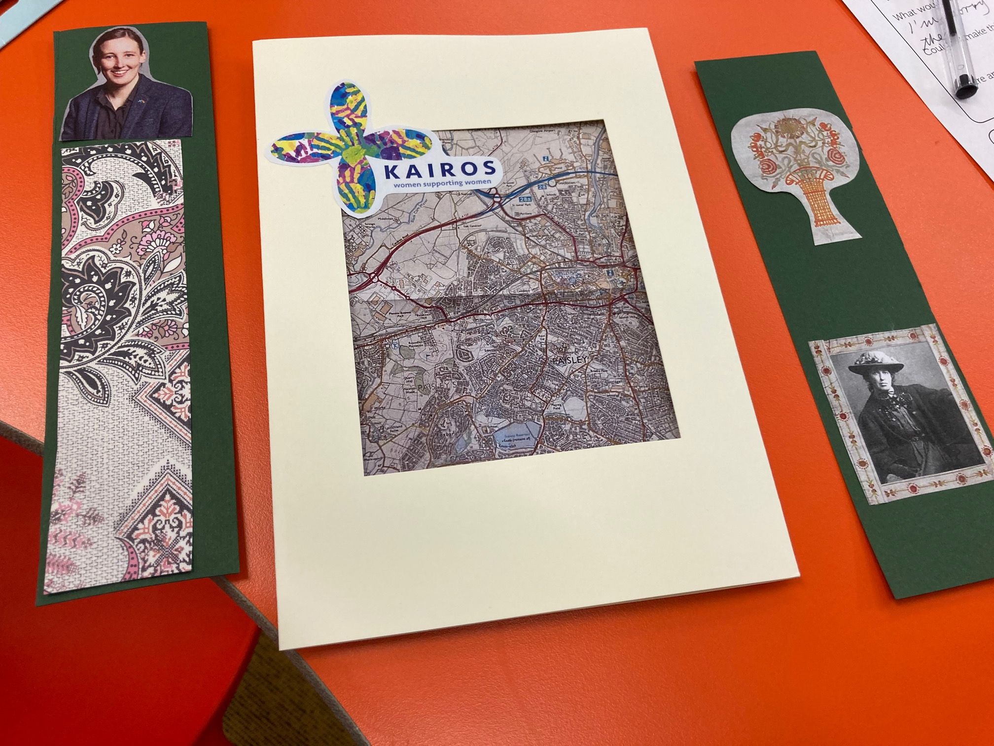 Coloured image of Image of a hand-made bookmark and hand-made card with pictures of Jessie Newbury and Mhairi Black Group of Making Her Mark participants in front of exhibition panels