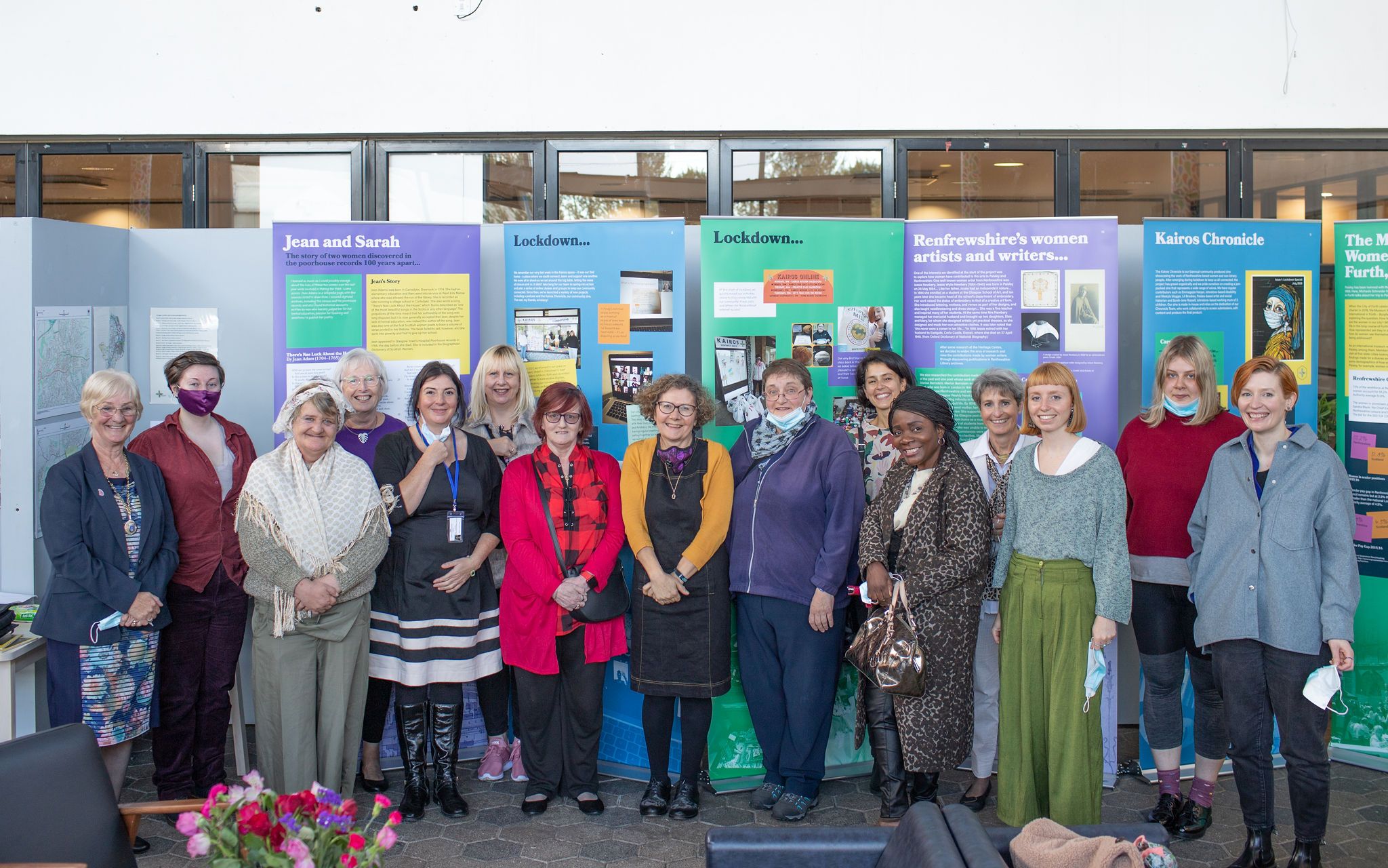 Colour image of a group of women standing in a line in front of museum exhibition panels.