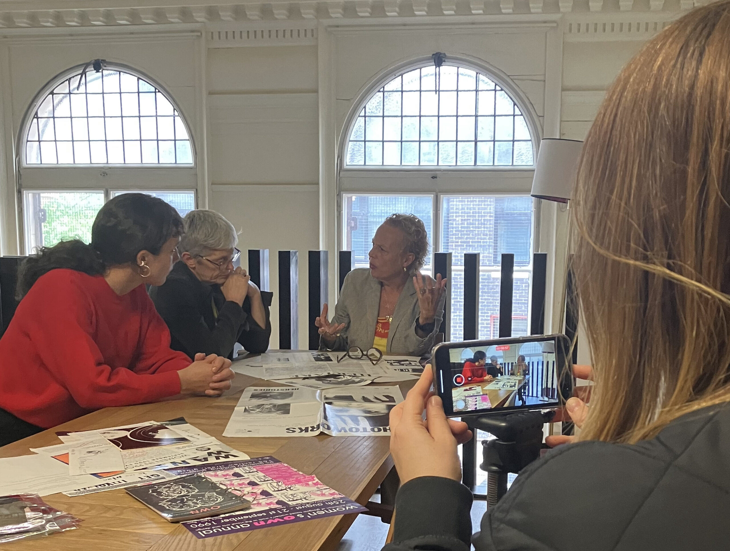 Adele Patrick, Kate Henderson and Mae Moss sit at a table on the GWL mezzanine looking at archive material.