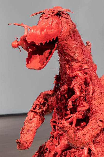 Close up image of a Red T-Rex sculpture made from mixed media plastics including toy soldiers