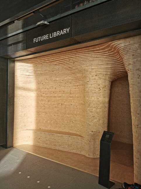a front view of aA curved wooden alcove entrance space, with Future Library signage