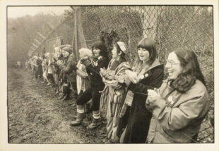 Black and whiyte images of a line of women along a barbed wire fence