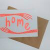 Two neon orange arms extend from either side of the card. The word Home is written in the same colour and looks cradled between the arms.