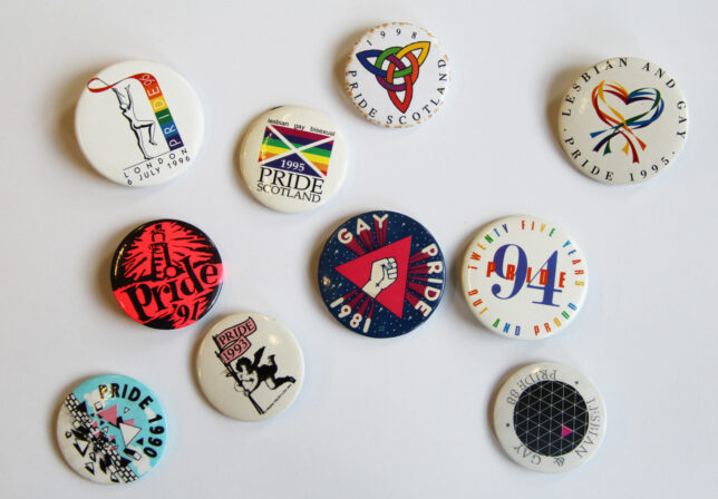 Selection of colourful Pride badges scattered on a white background.