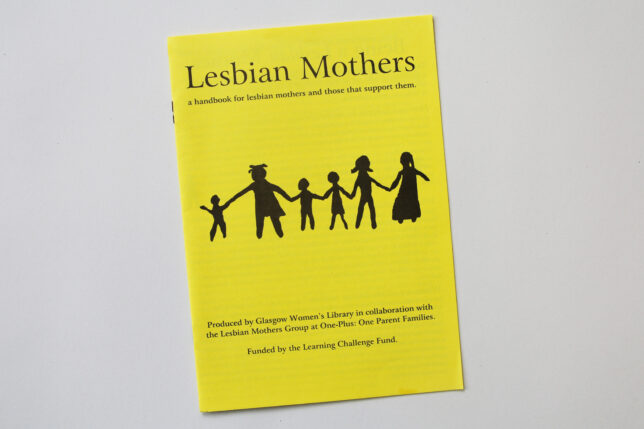 A photo of a handbook printed on bright yellow paper, the title reads 'Lesbian Mothers' and there is an image of a family in the style of a paper chain of dolls holding hands.
