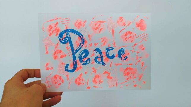 The word Peace is written in blue on a background of bright orange marks.