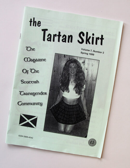 Photo shows cover of The Tartan Skirt. It features black and white photocopied text and images onto pale green paper. Text includes the name and date of the publication, there is a Scottish Flag and a photo of a Trans woman in a tartan skirt.