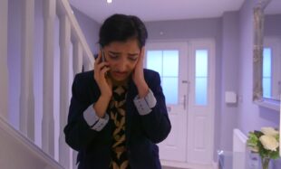 A photograph shows a school girl standing in the hallway of a home holding a phone to her ear and holding her other hand up to her face in distress.